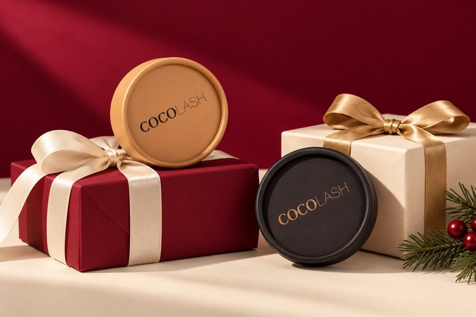 Gold and black CocoLash lash cases styled with cranberry and ivory wrapped presents and satin ribbon